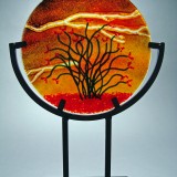 Circular fused glass art with silhouetted branches